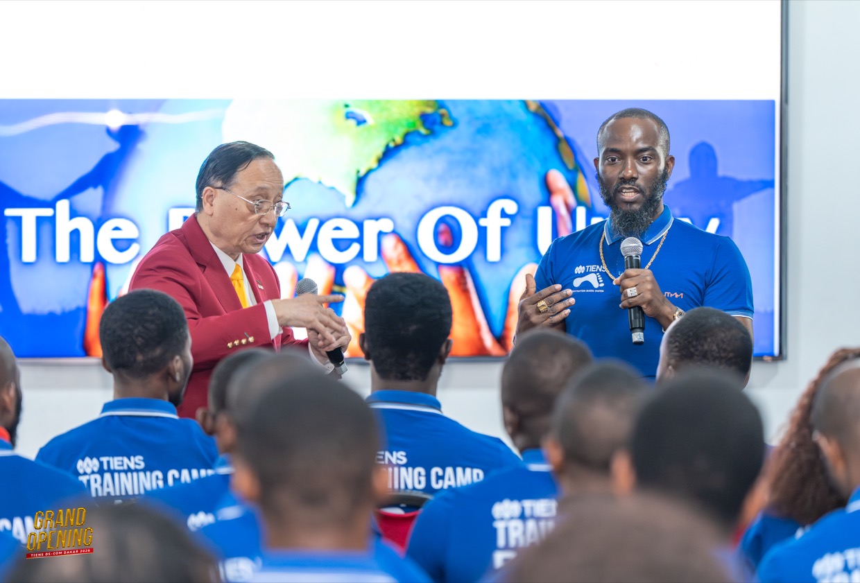 Un formateur TIENS DS-COM au micro devant un grand écran « Power of Unity »